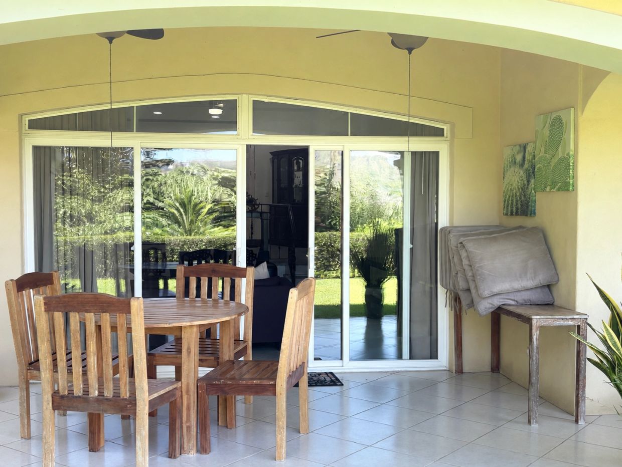 Terraza con mesa de madera y vista a jardín.