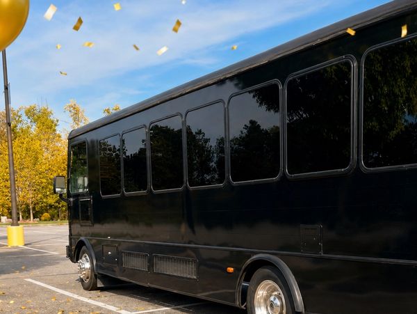 Black party bus with gold confetti falling outside.
