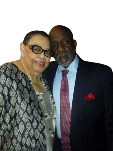 An elderly couple dressed elegantly, smiling and posing together.