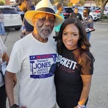 Two people smiling outdoors at a public event.