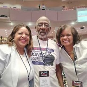 Three people smiling together at a conference or event indoors.