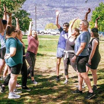 Group of people outdoors doing stretching exercises together.