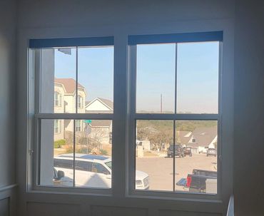 View of a suburban street through a window with parked cars and houses.