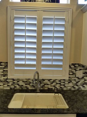 Modern kitchen sink with black granite countertop and mosaic tile backsplash.