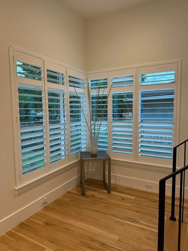 Corner with white plantation shutters and a small table with decorative vase.