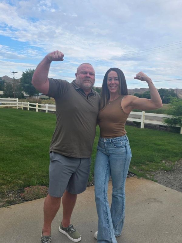 Man and woman flexing their arms outdoors.