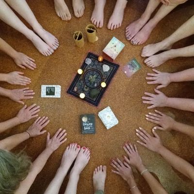 Several hands surrounding books and candles