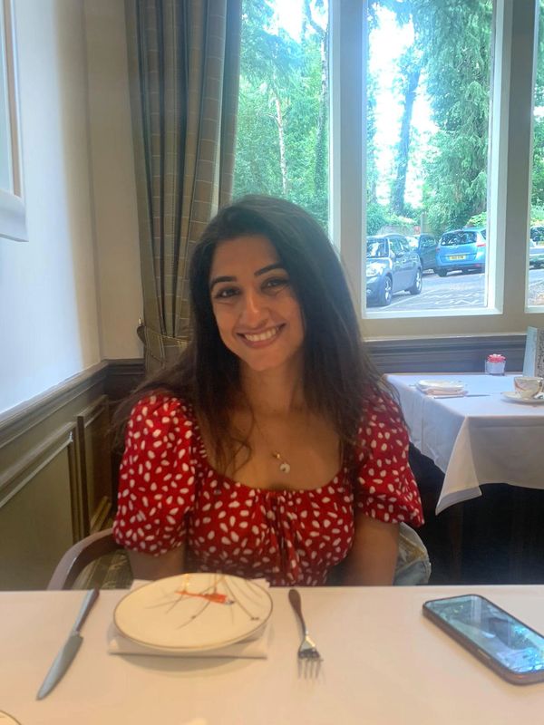 Smiling woman in a red dress sitting at a table in a restaurant.
