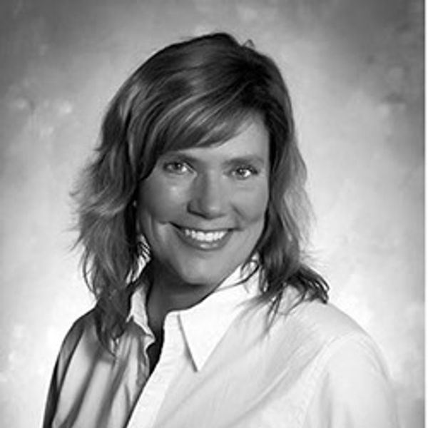 Black and white portrait of a smiling woman in a white shirt.