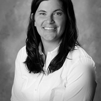 Black and white portrait of a smiling woman with dark hair in a white shirt.