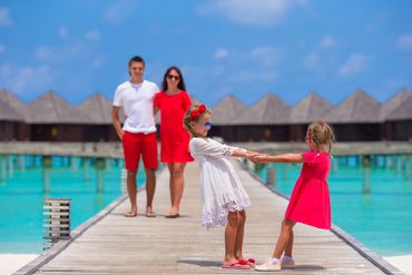 Cherished family moments unfold on the Maldives’ serene overwater walkways, where children lead the