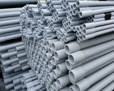Stacks of gray PVC conduits arranged in bundles.