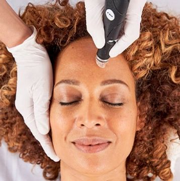 A woman receiving a facial treatment with a skin care device.