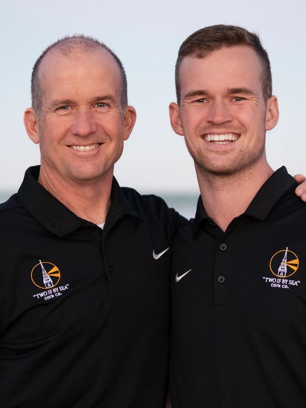 Two men smiling, wearing matching black polo shirts with a logo.