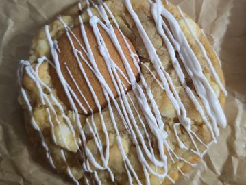 A cookie with a vanilla wafer center drizzled with white icing.