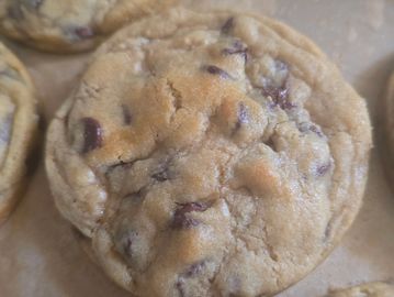 Close-up of freshly baked chocolate chip cookies on parchment paper.