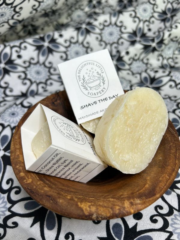 Handmade shaving soap bars in a wooden bowl with decorative packaging.