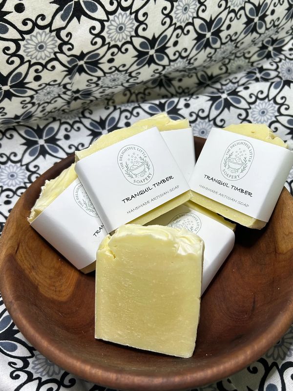 Handmade artisan soap bars labeled 'Tranquil Timber' in a wooden bowl.