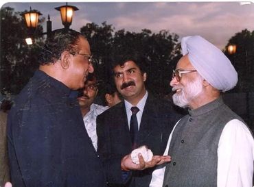 Three men engaged in a conversation during an outdoor evening event.