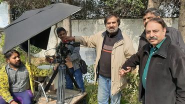 Group of men around professional camera equipment outdoors.