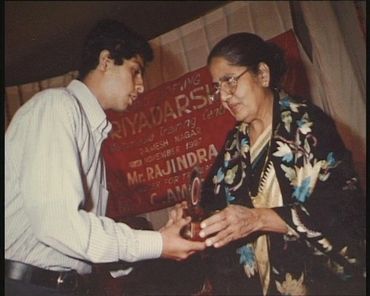 A young man receives an award from an elderly woman at an event.