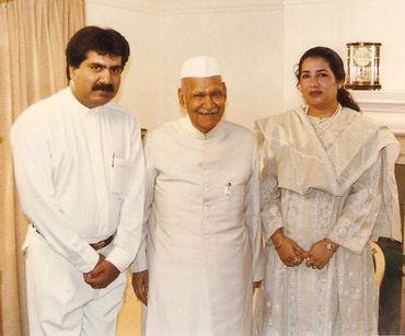 Three people posing indoors in traditional attire, smiling for the camera.