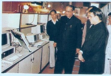 Group of men observing vintage computer monitors in a retro setting.