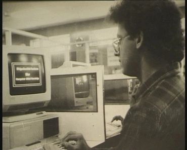 A man using a vintage computer in an office or lab setting.