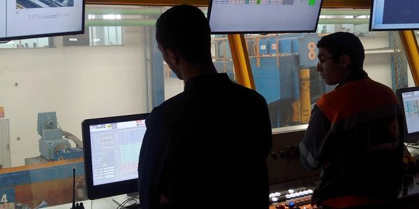 Man monitoring machinery through a computer screen in a control room.