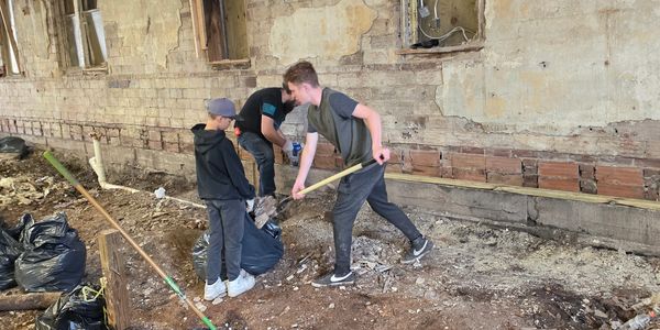 Boys cleaning a rundown building's interior.