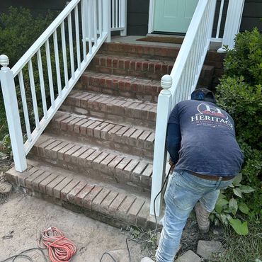 Mason starting work on worn front brick steps with white railings, Richmond VA – before