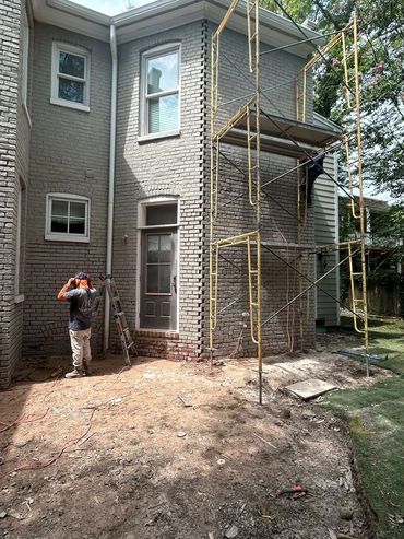 Heritage mason at scaffolding on a painted brick townhouse wall, Richmond VA