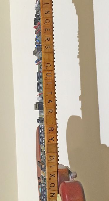Artist signature is written with found scrabble letters on the electric guitar neck