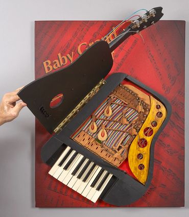 Open piano sculpture exposes found piano parts, electric wires and wood combined in a small assembla