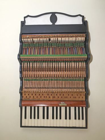 Wall hanging sculpture of piano parts on wood