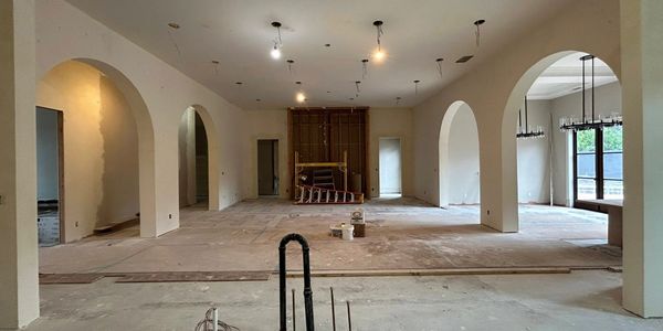 Spacious living room under renovation with beautiful arched doorways and added lighting.