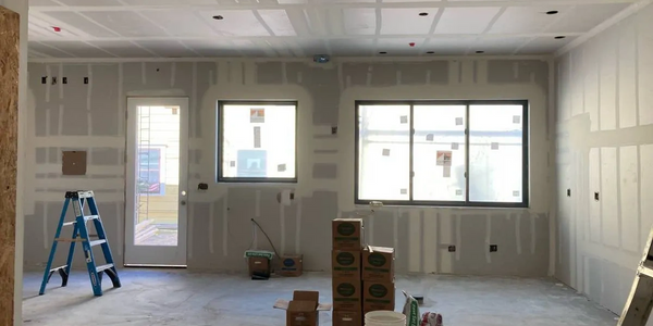 Room under construction with drywall and construction materials scattered.