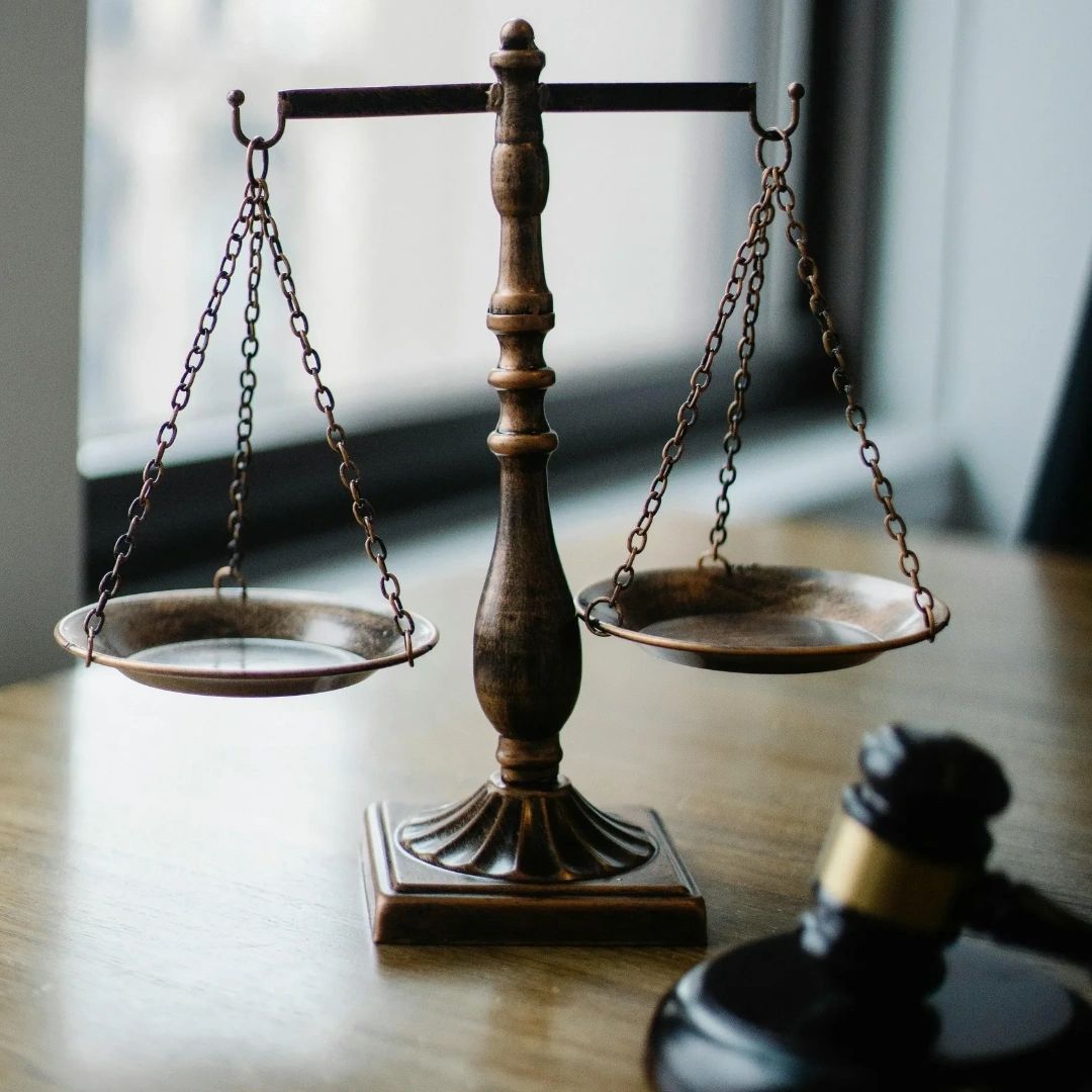 Antique balance scale and judge gavel on wooden table.