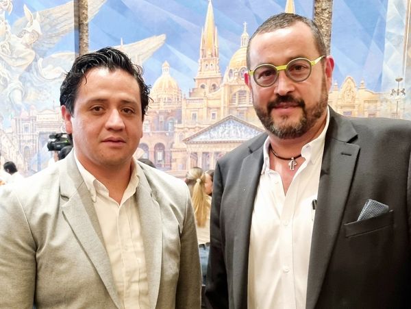 Dos hombres vestidos formalmente posan juntos.