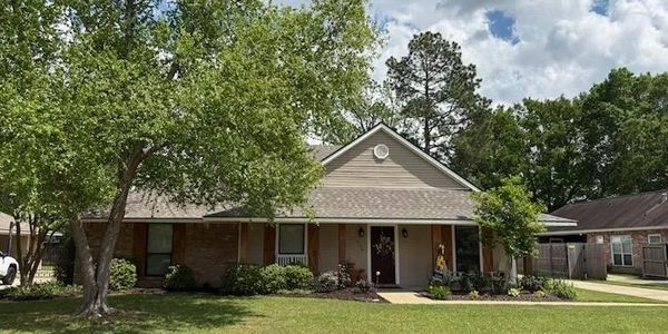 Single-story suburban house with a large front yard and trees.