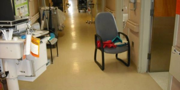 A chair in a hospital corridor with medical equipment nearby.