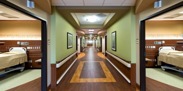 Empty hospital hallway with patient rooms on both sides.