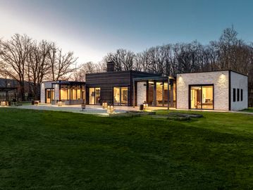 Modern house with large windows illuminated at dusk.