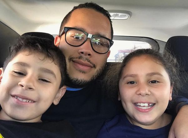 Man with two smiling children inside a car.