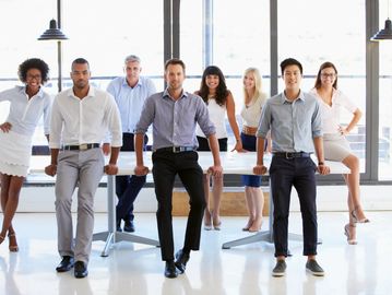 A group of seven professionals posing confidently in an office.