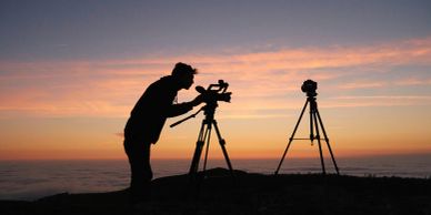 Silhouette of a person using a camera at sunset.