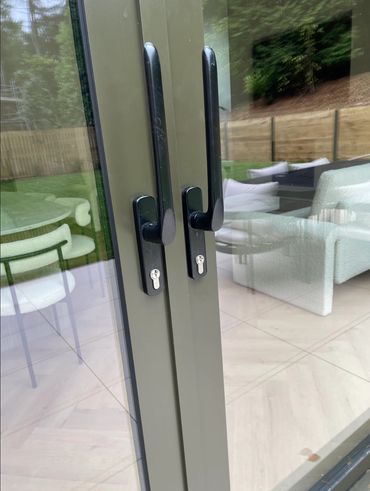 Modern glass doors with black handles reflecting a cozy indoor setting.