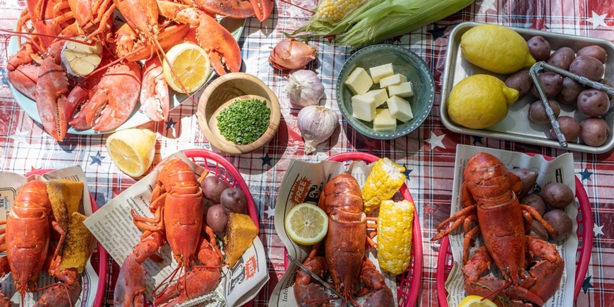 Photo of cooked Maine lobsters, corn on the cob, lemons, potatoes, like the lobsters sold at Crabby 