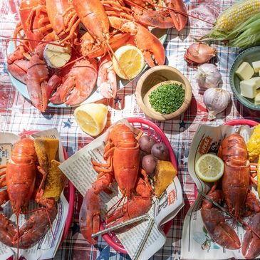Cooked lobsters, lemon, spices on tablecloth with utensils for eating - Crabby Lobster Seafood