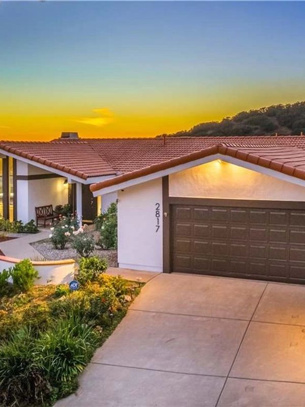 Modern house with a tiled roof and a sunset sky in the background.